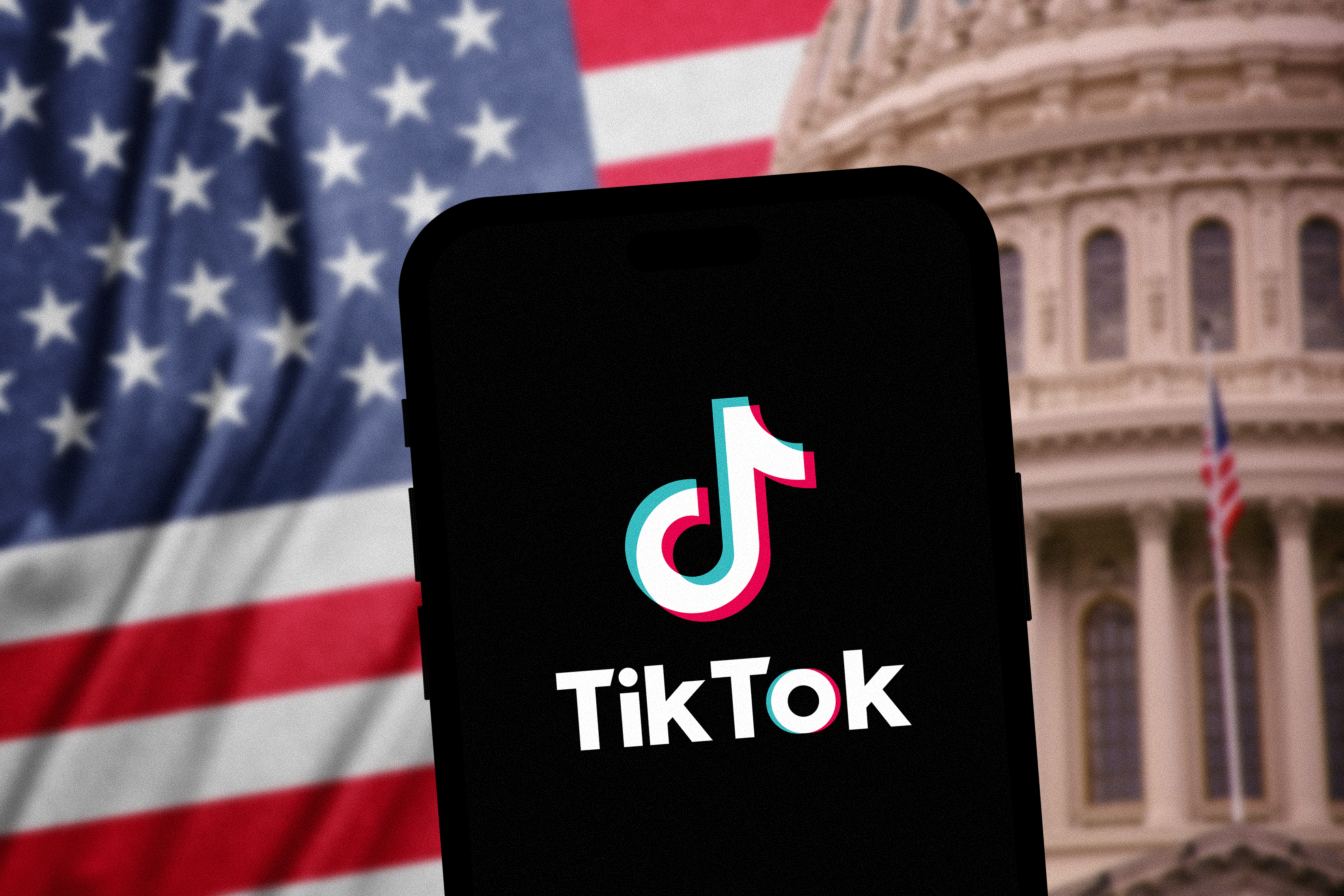 米国ワシントン - 2024年3月4日：電話でのTikTokロゴ – 前景がシャープで、アメリカ議会の建物と米国の国旗が背景にぼやけている、米国でのTikTok禁止の概念。
